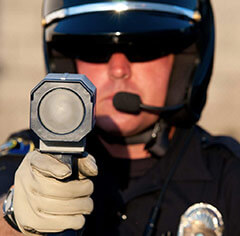 a police officer holding his radar gun and pointing it at traffic.